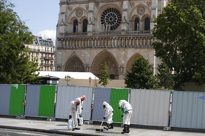 Workers clean the area in front of Notre Dame cathedral, Monday, Aug. 19, 2019 in Paris. Specialists shoring up fire-damaged Notre Dame Cathedral were returning to the Paris site on Monday for the first time in nearly a month, this time wearing disposable underwear and other protective gear after a delay prompted by fears of lead contamination. (AP Photo/Francois Mori)