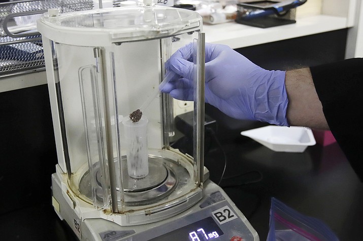 In this Friday, Aug. 16, 2019, photo, chemist David Dawson pours pieces of a cannabis-infused chocolate bar into a vial as he demonstrates testing for THC and other chemicals at CW Analytical Laboratories in Oakland, Calif. Chemists are trying to solve a scientific mystery involving marijuana brownies. Chocolate seems to throw off test results for potency. That could be dangerous for consumers looking to relax, not hallucinate. (AP Photo/Jeff Chiu)