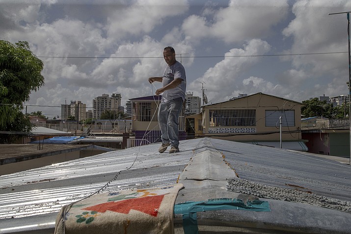 Jorge Ortiz works to tie down his roof as he prepares for the arrival of Tropical Storm Dorian, in the Martín Peña neighborhood of San Juan, Puerto Rico, Tuesday, Aug. 27, 2019. The 50-year-old construction worker was taking no chances as Dorian approached Puerto Rico on Tuesday and threatened to brush past the island's southwest coast at near-hurricane strength. (AP Photo/Gianfranco Gaglione)