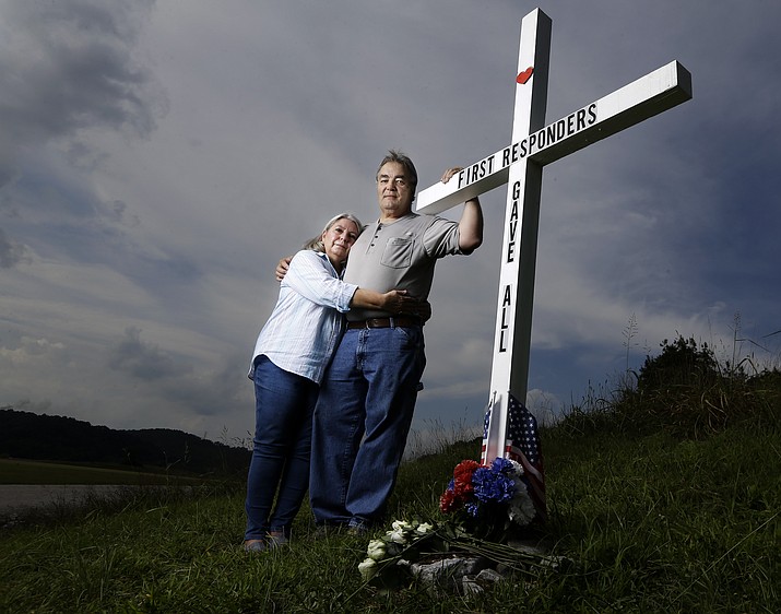 In this Aug. 6, 2019, photo, Ansol and Janie Clark pose at a memorial Ansol Clark constructed near the Kingston Fossil Plant in Kingston, Tenn. The Tennessee Valley Authority was responsible for a massive coal ash spill at the plant in 2008 that covered a community and fouled rivers. The couple says the memorial is for the workers who have come down with illnesses, some fatal, including cancers of the lung, brain, blood and skin and chronic obstructive pulmonary disease. Ansol Clark drove a fuel truck for four years at the cleanup site, and now suffers from a rare blood cancer. (AP Photo/Mark Humphrey)