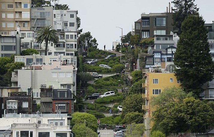 In this April 15, 2019, file photo, cars wind their way down Lombard Street in San Francisco. Thousands of tourists could soon be forced to make reservations and pay to drive the famed crooked Lombard Street in San Francisco. California lawmakers approved a bill Thursday, Sept. 5, 2019, granting San Francisco the power to establish a toll and reservation system for Lombard Street. The bill still needs Gov. Gavin Newsom's signature. The San Francisco County Transportation Authority has suggested $5 per car weekdays and $10 weekends and holidays. (AP Photo/Eric Risberg, File)