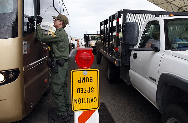 This July 27, 2010, file photo shows a Border Patrol agent checks the identification card of a bus driver at a checkpoint in Amado. A judge who says he repeatedly heard defendants over the years deny knowledge of drugs found in their cars says that the despicable conduct of three leaders of a smuggling ring now makes him wonder whether the denials were true. U.S. District Judge Raner C. Collins on Sept. 9, 2019, sentenced the smuggling ring leaders, who had pleaded guilty, to prison terms ranging from 8 to 10 years. (Jae C. Hong/AP, file)