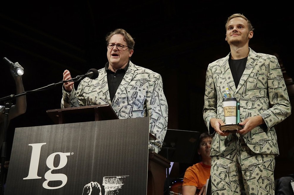 Andreas Voss, left, and his son Timothy Voss, of The Netherlands, receive the Ig Nobel award in economics for testing which country's paper money is best at transmitting dangerous bacteria, at the 29th annual Ig Nobel awards ceremony at Harvard University, Thursday, Sept. 12, 2019, in Cambridge, Mass. The spoof prizes for weird and sometimes head-scratching scientific achievement are bestowed by the Annals of Improbable Research magazine, and handed out by real Nobel laureates. (AP Photo/Elise Amendola)