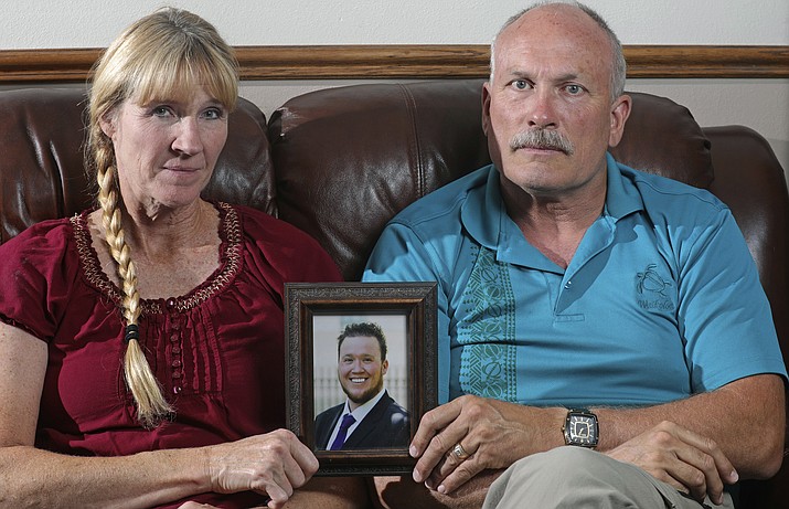 In this Monday, Sept. 9, 2019, photo, Rod and Tonya Meldrum hold a portrait of their son Devin Meldrum, in Provo, Utah. He suffered from debilitating cluster headaches and fatally overdosed after taking a single fentanyl-laced counterfeit oxycodone pill purchased from a dark-web store run by Aaron Shamo, according to his family and authorities. Shamo was not charged in Meldrum’s death, and his lawyers have argued that and other alleged overdoses can’t be definitively linked to him. (Rick Bowmer/AP)