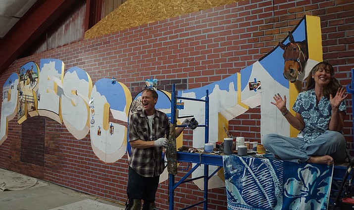 Local artists Dana Cohn, left, and Julie Hutchins, who are working together on a large “Prescott” mural for the Whiskey Row alley, talk about the details of the weeks-long project. The mural, which is being created in a workspace at the Prescott Rodeo Grounds, is expected to be installed in the alley in late October or early November. (Cindy Barks/Courier)