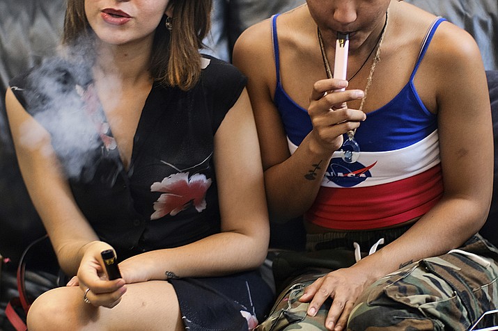 In this Saturday, June 8, 2019 file photo, two women smoke cannabis vape pens at a party in Los Angeles. On Friday, Sept. 27, 2019, the Centers for Disease Control and Prevention said more than three-quarters of the 805 confirmed and probable illnesses from vaping involved THC, the ingredient that produces a high in marijuana. (AP Photo/Richard Vogel)