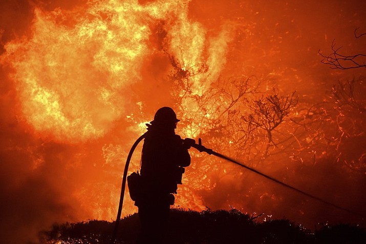 The Saddleridge fire flares up near a firefighter in Sylmar, Calif., Thursday, Oct. 10, 2019. (AP Photo/Michael Owen Baker)