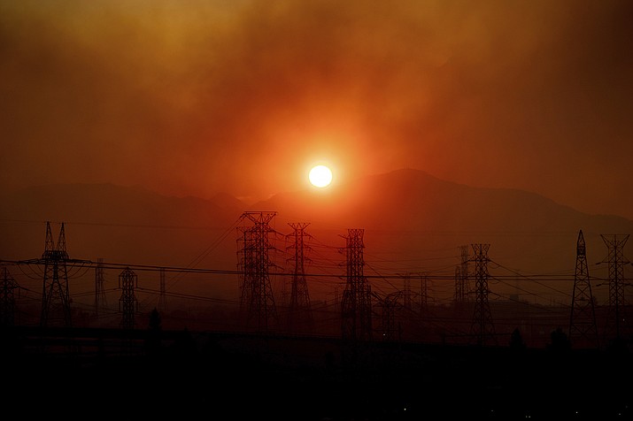 Smoke from the Saddleridge Fire hangs above power lines as the sun rises in Newhall, Calif., on Friday, Oct. 11, 2019. An aggressive wildfire in Southern California seared its way through dry vegetation Friday and spread quickly, destroying more than a dozen homes as tens of thousands of residents were ordered to get out of its way, authorities said. (AP Photo/Noah Berger)