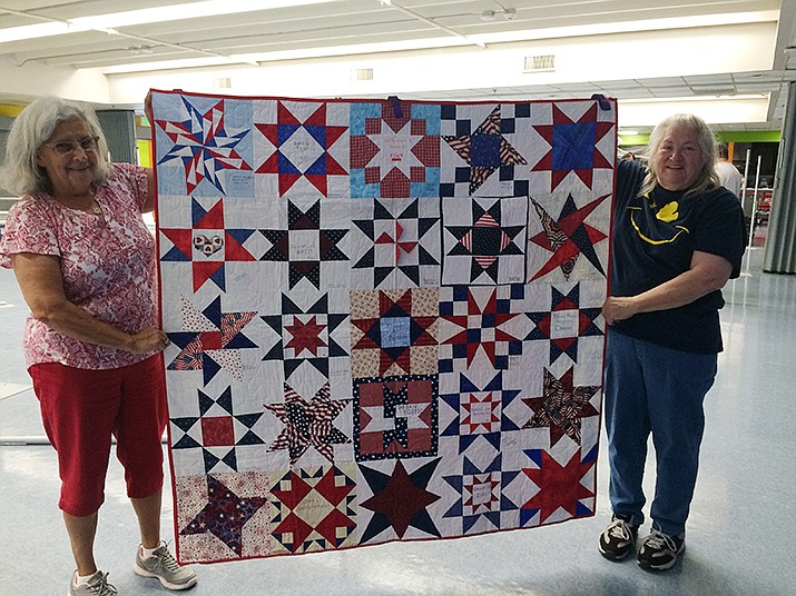 Keeper of the quilts Beverly Kuemin of Michigan (right) and Marlene Baker (left) hold up one of the quilt panels is part of the patriotic-themed 9/11 WTC memorial quilt. (Nanci Hutson/Courier)