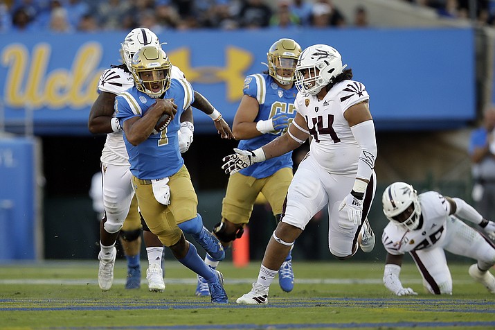 UCLA quarterback Dorian Thompson-Robinson, left, is chased by Arizona State defensive lineman T.J. Pesefea (44) during the first half of a game Saturday, Oct. 26, 2019, in Pasadena, Calif. (Marcio Jose Sanchez/AP)