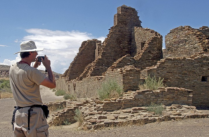 In this Aug. 10, 2005 file photo, tourist Chris Farthing from Suffolks County, England, takes a picture of Anasazi ruins in Chaco Culture National Historical Park in New Mexico. The checkerboard of federal land surrounding Chaco Culture National Historical Park would be off limits to oil and gas development under legislation pending before Congress. The U.S. House is set to vote on the measure Wednesday, Oct. 30, 2019. (AP Photo/Jeff Geissler, File)