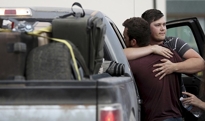 Cole Langford, left, and Hayden Spenct, of the Mormon colony in La Mora, Mexico, hug during a rendezvous in a gas station in Douglas, Ariz., Saturday, Nov. 9, 2019. Family and friends said goodbye Saturday to the last victim of a cartel ambush that killed nine American women and children from a Mormon community in northern Mexico where cartels have disrupted an otherwise peaceful, rural existence. (Kelly Presnell/Arizona Daily Star via AP)