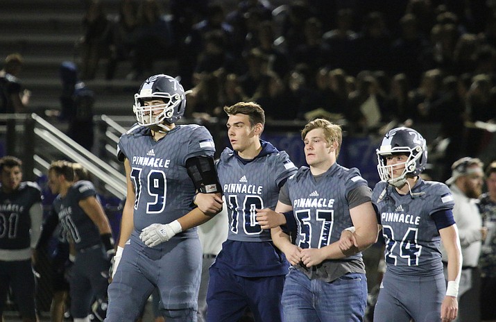 Tosh Baker (79), Adam Verbalatis (57) and Clay Zupke (24) walk down the field with J.D. Johnson (10) during their home game against the Boulder Creek Jaguars. (Photo by Cassidy McCauley/Cronkite News)
