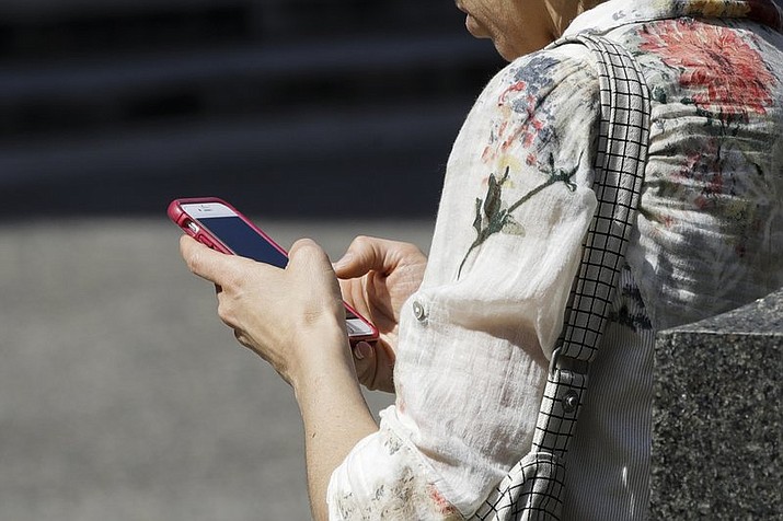 In this April 8, 2019, file photo, a woman browses her smartphone in Philadelphia. Accidental cuts and bruises to the face, head and neck from cellphones are sending increasing numbers of Americans to the emergency room, according to a study that estimates 76,000 cases over nine years. (AP Photo/Matt Rourke, File)