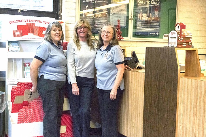 Grand Canyon postal employees Katrina Granstrom, Krissy Root and Jennifer Hill pose inside the decorated Grand Canyon Post Office where they will see between 300-600 packages per day during the busy Christmas season. (V. Ronnie Tierney/WGCN)