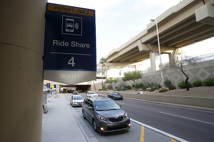 Vehicles wait for their passengers at the Ride Share pickup point at Phoenix Sky Harbor International Airport Wednesday, Dec. 18, 2019, in Phoenix. The Phoenix City Council is set to vote on raising fees charged to ride-hailing companies at the airport. If approved Wednesday afternoon, the proposal will increase the current fee from $2.66 per pickup. That would jump to $4 starting Jan. 1 and be applied to drop-offs as well. (AP Photo/Ross D. Franklin)