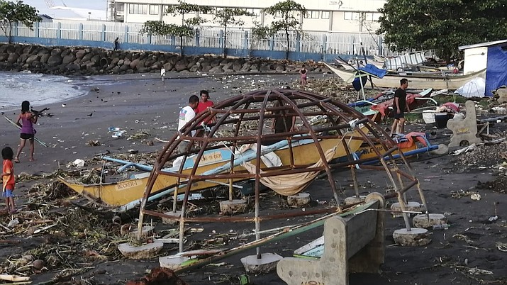 Residents walks beside an outrigger and playground equipment that were damaged by Typhoon Phanfone along a coastline in Ormoc city, central Philippines on Thursday Dec. 26, 2019. The typhoon left over a dozen dead and many homeless. (AP Photo)