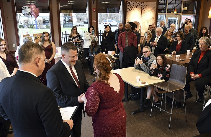 Jason Roy and Valerie Sneade say their vows in front of friends and family at the Dunkin' Donuts on Friday, Dec. 27, 2019 in Worcester, Mass. The couple reunited for their wedding vows at the Dunkin' Donuts where their young love splintered nearly thirty years ago. Except for a couple of chance encounters, Sneade and Roy mostly didn't see each other for 25 years after a conversation about their future at the same donut shop in 1992 led the young couple to slowly cut ties. Sneade and Roy blame misunderstandings at the time and words that didn't come out right. (Rick Cinclair/Worcester Telegram &amp; Gazette via AP)