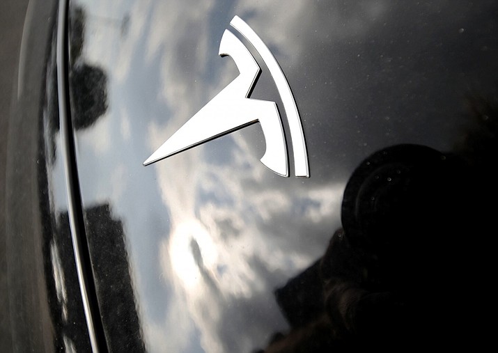 Clouds are reflected above the logo on the hood of a Tesla vehicle outside a showroom in Littleton, Colo. The National Highway Traffic Safety Administration is investigating the crash of a speeding Tesla that killed two people in a Los Angeles suburb, the agency announced Tuesday, Dec. 31, 2019. (David Zalubowski, File/Associated Press)