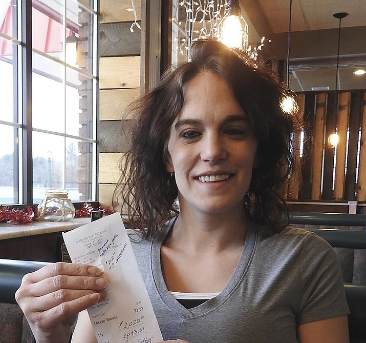 In this Dec. 30, 2019 photo, server Danielle Franzoni holds a receipt from a customer with a $2,020 tip included at Thunder Bay River Restaurant in Alpena, Mich. The credit card receipt said "Happy New Year. 2020 Tip Challenge." Franzoni, a single mother, couldn't believe the number, but her manager assured her the tip was legitimate. She said she was living in a homeless shelter a year ago. Franzoni plans to use the money to reinstate her driver's license and build savings. (Julie Riddle/The News via AP)