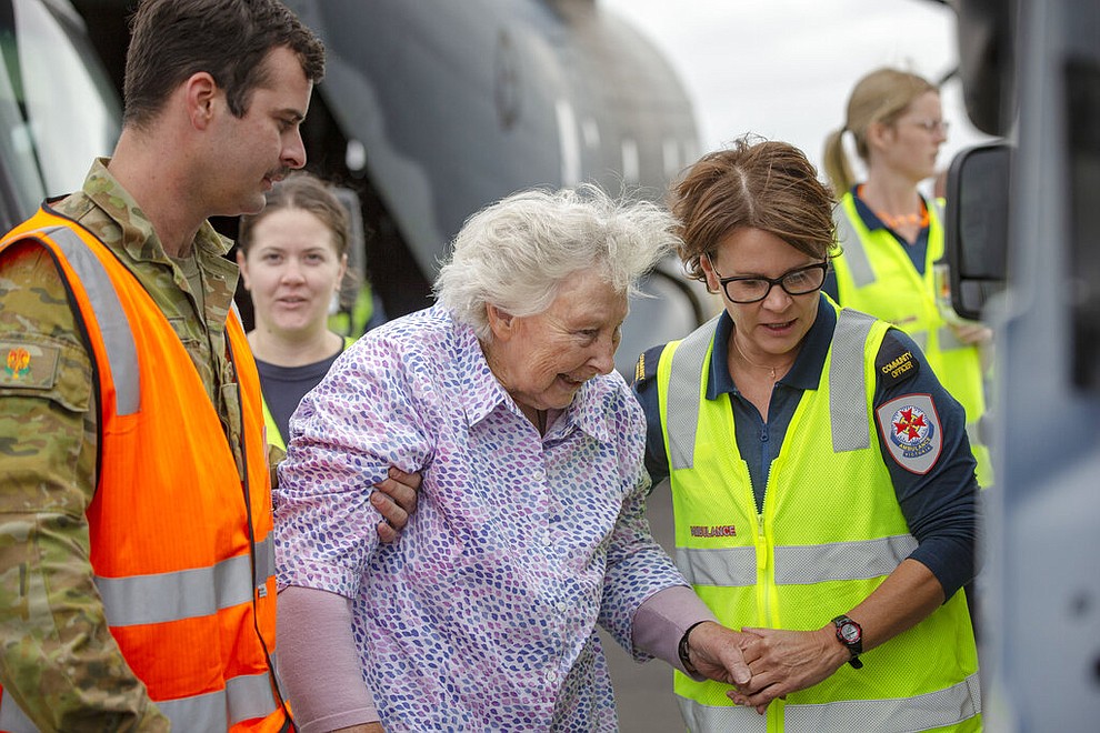 In this Jan. 5, 2020, photo provided by the Australian Department of Defence, Australian Army Soldier, Corporal Storm Sharp, left, and a paramedic, right, assist a woman at Sale after the evacuation of fire effected areas of Australia's south east. The wildfires have so far scorched an area twice the size of the U.S. state of Maryland.(Corporal Nicole Dorrett/ADF via AP)