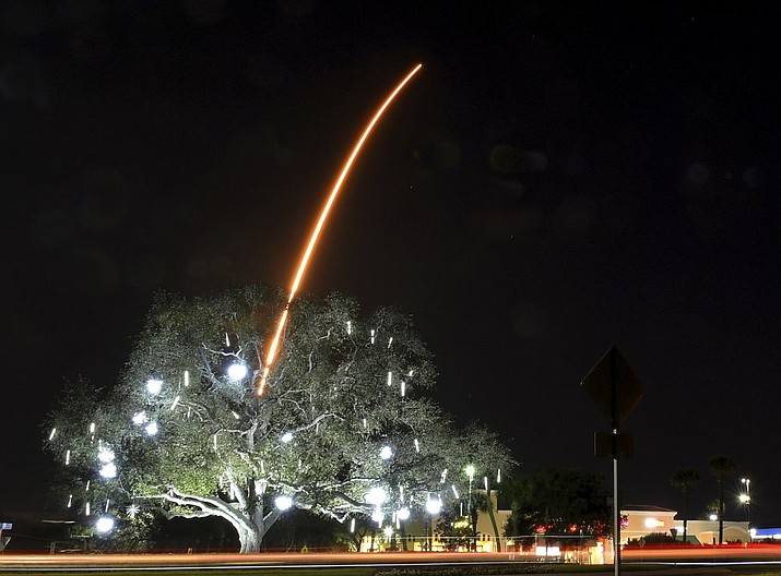 In a time exposure, the SpaceX Falcon 9 rocket launches from Cape Canaveral, as seen from Viera, Fla., late Monday, Jan. 6, 2020. In the foreground is the traffic roundabout, which is lit up for the holiday season. (Tim Shortt/Florida Today via AP)