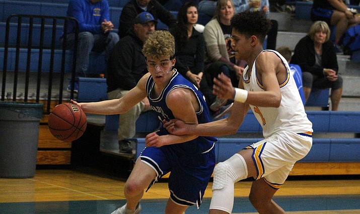 Academy senior Connor Alleman, left, drives past Kingman's Eddie Howery. Alleman scored a game-high 22 points to help the Tigers knock off the Bulldogs 64-59 Thursday at KHS. (Photo by Beau Bearden/Kingman Miner)