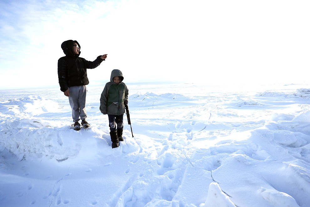 In this Saturday, Jan. 18, 2020, photo, George Chakuchin, left, and Mick Chakuchin look out over the Bering Sea near Toksook Bay, Alaska. The first Americans to be counted in the 2020 Census starting Tuesday, Jan. 21, live in this Bering Sea coastal village. The Census traditionally begins earlier in Alaska than the rest of the nation because frozen ground allows easier access for Census workers, and rural Alaska will scatter with the spring thaw to traditional hunting and fishing grounds. (AP Photo/Gregory Bull)