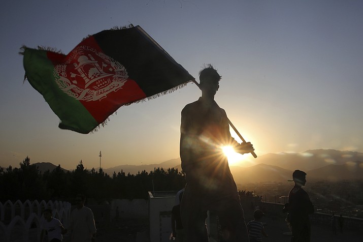 In this Aug. 19, 2019, file photo, a man waves an Afghan flag during Independence Day celebrations in Kabul, Afghanistan. An Afghan official Sunday, Feb. 9, 2020, said multiple U.S. military deaths have been reported in Afghanistan's Nangarhar province after an insider attack by a man wearing an Afghan army uniform. (Rafiq Maqbool/AP file)