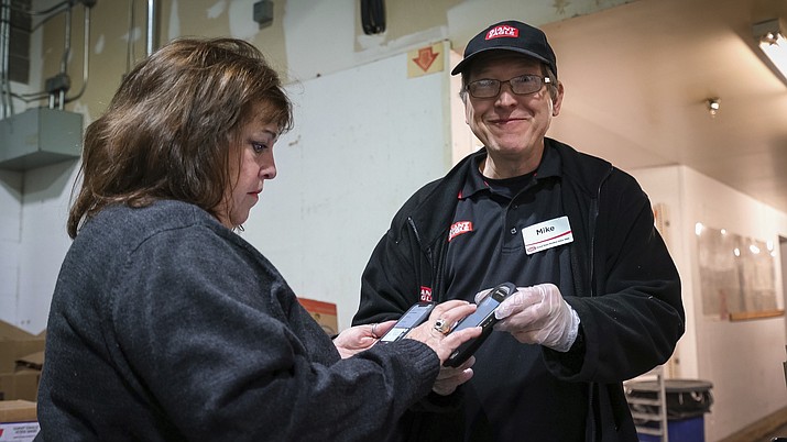 This Oct. 20, 2019 photo released by 412 Food Rescue shows a volunteer using the Food Rescue Hero app to check in at a Pittsburgh grocery store to pick up donated food. (Monica Godfrey-Garrison/412 Food Rescue via AP)