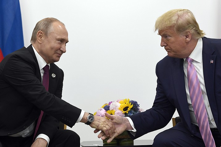 In this June 28, 2019, file photo, President Donald Trump, right, shakes hands with Russian President Vladimir Putin, left, during a bilateral meeting on the sidelines of the G-20 summit in Osaka, Japan. Intelligence officials say Russia is interfering with the 2020 election to try to help Trump get reelected, The New York Times reported Thursday, Feb. 20, 2020. (Susan Walsh/AP, file)