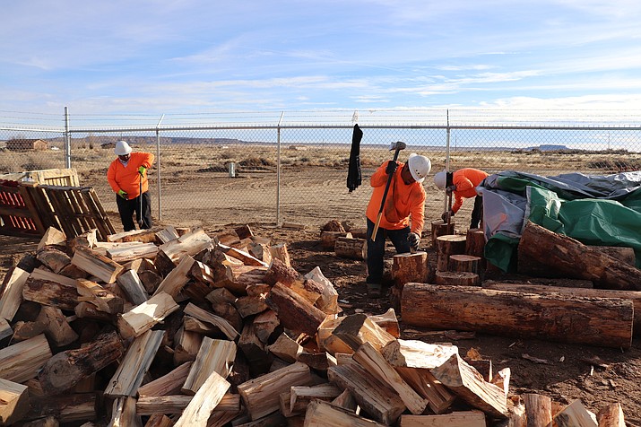 In this Dec. 6, 2019, photo, workers employed by the Village of Tewa chop wood delivered from the White Mountain Apache Timber Company in the Village of the Tewa administration building on the Hopi Nation, in Arizona. Navajo and Hopi families in northeastern Arizona that have long relied on coal to heat their homes are looking to other sources after last year's closure of a coal mine. (Melissa L. Sevigny/Arizona Public Radio via AP)