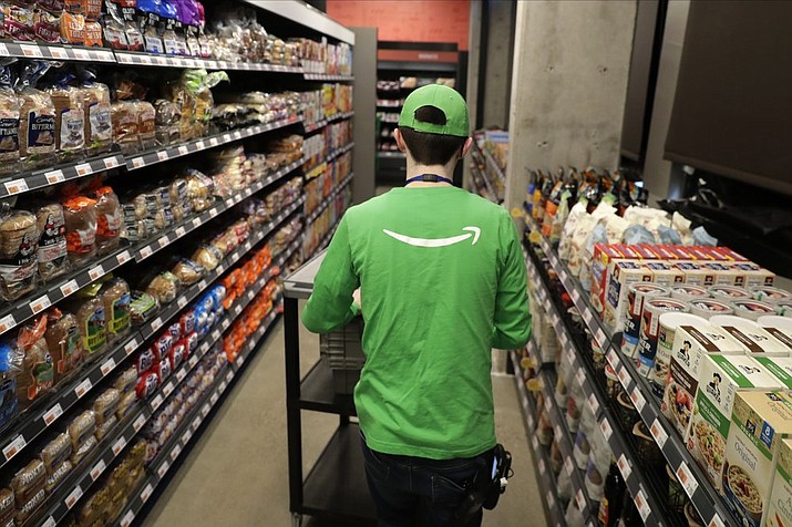 In this Feb. 21, 2020 photo, a worker pushes a cart inside an Amazon Go Grocery store set to open soon in Seattle's Capitol Hill neighborhood. Following the opening of several smaller convenience-type stores using an app and cashier-less technology to tally shoppers' selections, the store will be the first Amazon Go full-sized cashier-less grocery store. (AP Photo/Ted S. Warren)