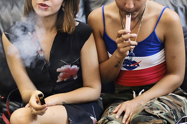 Two young women smoke cannabis vape pens in this 2019 image. At a Feb. 25, 2020, forum at the Prescott Valley library, panelists said parents or guardians must intervene if they suspect their son or daughter is vaping. (Richard Vogel/AP file)