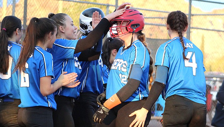 Academy junior Kiley Holloway (12) is surrounded by teammates Friday after hitting a two-run homer in the first inning against Lee Williams. The Lady Tigers won the game 11-1 in six innings. (Photo by Beau Bearden/Kingman Miner)