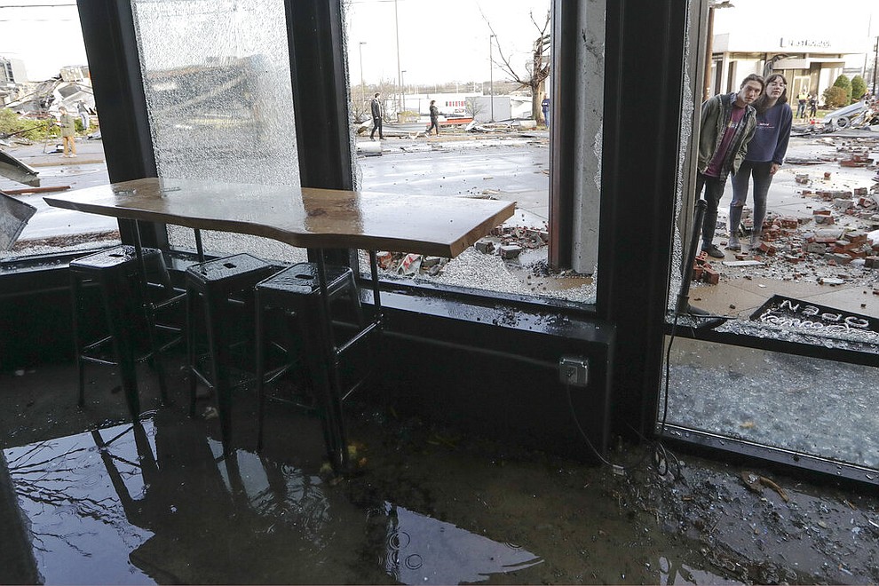 People look in a restaurant damaged by storms Tuesday, March 3, 2020, in Nashville, Tenn. Tornadoes ripped across Tennessee early Tuesday, shredding buildings and killing multiple people. (AP Photo/Mark Humphrey)