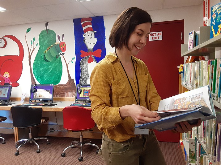 Chino Valley Youth Librarian Rebecca Laurence looks at one of the children’s books in the library that she could possibly use for an upcoming storytime Thursday morning, Feb. 27. (Jason Wheeler/Review)