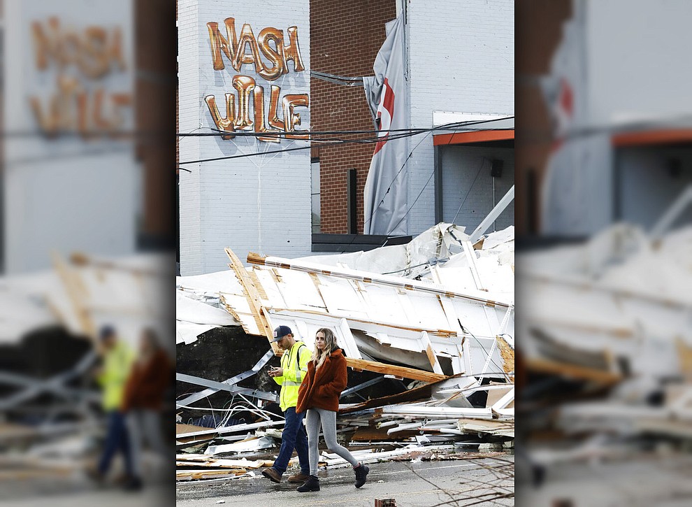People walk past storm debris following a deadly tornado, Tuesday, March 3, 2020, in Nashville, Tenn. Tornadoes ripped across Tennessee early Tuesday, shredding buildings and killing multiple people. (AP Photo/Mark Humphrey)