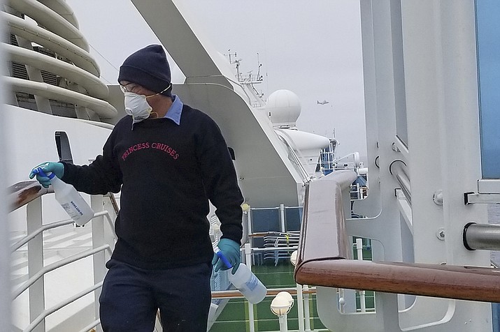A cruise ship worker cleans a railing on the Grand Princess Thursday, March 5, 2020, off the California coast. Scrambling to keep the coronavirus at bay, officials ordered a cruise ship with about 3,500 people aboard to stay back from the California coast until passengers and crew can be tested, after a traveler from its previous voyage died of the disease and at least two others became infected. (Michele Smith via AP)