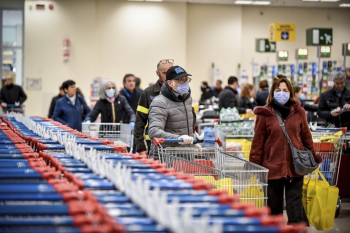 People wear masks at a supermarket in Milan, Italy, Sunday, March 8, 2020. Italy announced a sweeping quarantine early Sunday for its northern regions, igniting travel chaos as it restricted the movements of a quarter of its population in a bid to halt the new coronavirus' relentless march across Europe. (Claudio Furlan/LaPresse via AP)
