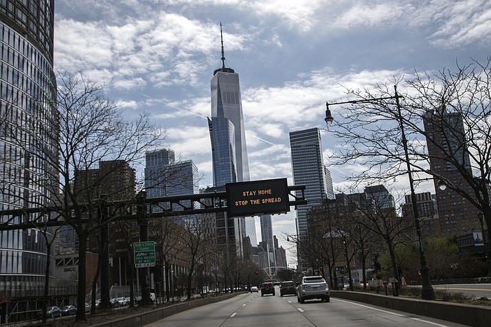 An electronic sign board urging citizens to stay home and stop the spread of the coronavirus is seen displayed above a road in the foreground of One World Trade Center in New York, on Sunday, March 22, 2020. (Wong Maye-E/AP photo)