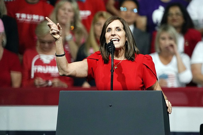 In this Feb. 19, 2020 photo, Sen. Martha McSally, R-Arizona, speaks at a rally for President Donald Trump in Phoenix. McSally is volunteering at the Salvation Army. Her challenger, Mark Kelly, is using his background as an astronaut to entertain kids stuck at home. The global pandemic that is shaking up life is also forcing Arizona's U.S. Senate candidates to reinvent the political playbook when voters are much more concerned about staying healthy and paying the bills than they are with politics. (Rick Scuteri/AP, file)