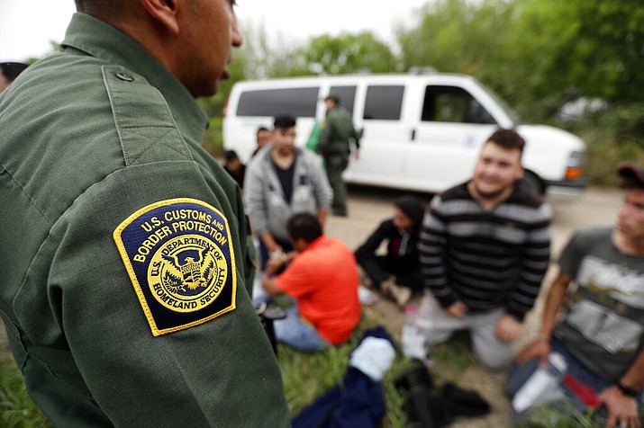 In this Thursday, March 14, 2019, file photo, a Border Patrol agent talks with a group suspected of having entered the U.S. illegally near McAllen, Texas. The Trump administration has quietly shut down the nation's asylum system for the first time in decades amid coronavirus concerns, largely because holding people in custody is considered too dangerous. (AP Photo/Eric Gay, File)