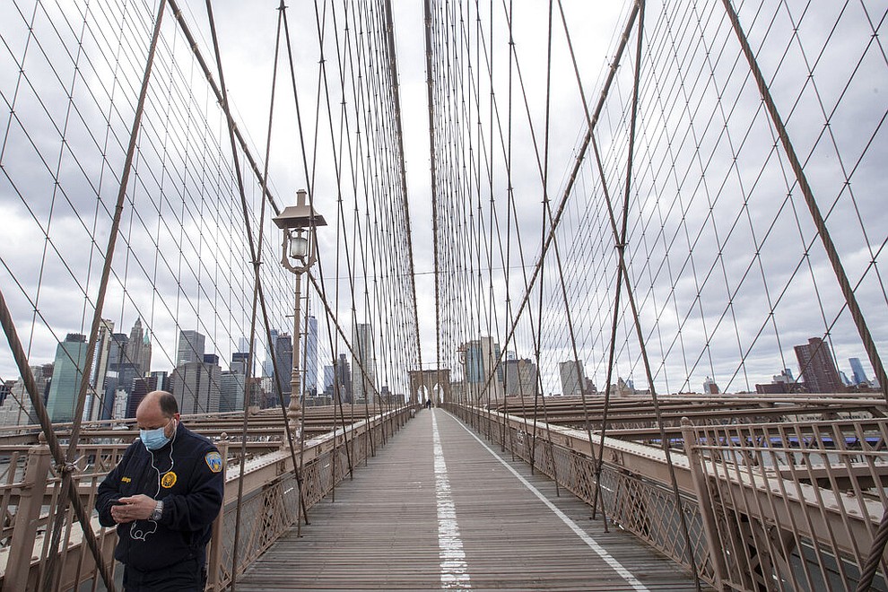 A man wears a face mask for protection against the coronavirus as he walks over the Brooklyn Bridge, Friday, April 10, 2020, in New York. The new coronavirus causes mild or moderate symptoms for most people, but for some, especially older adults and people with existing health problems, it can cause more severe illness or death. (AP Photo/Mary Altaffer)