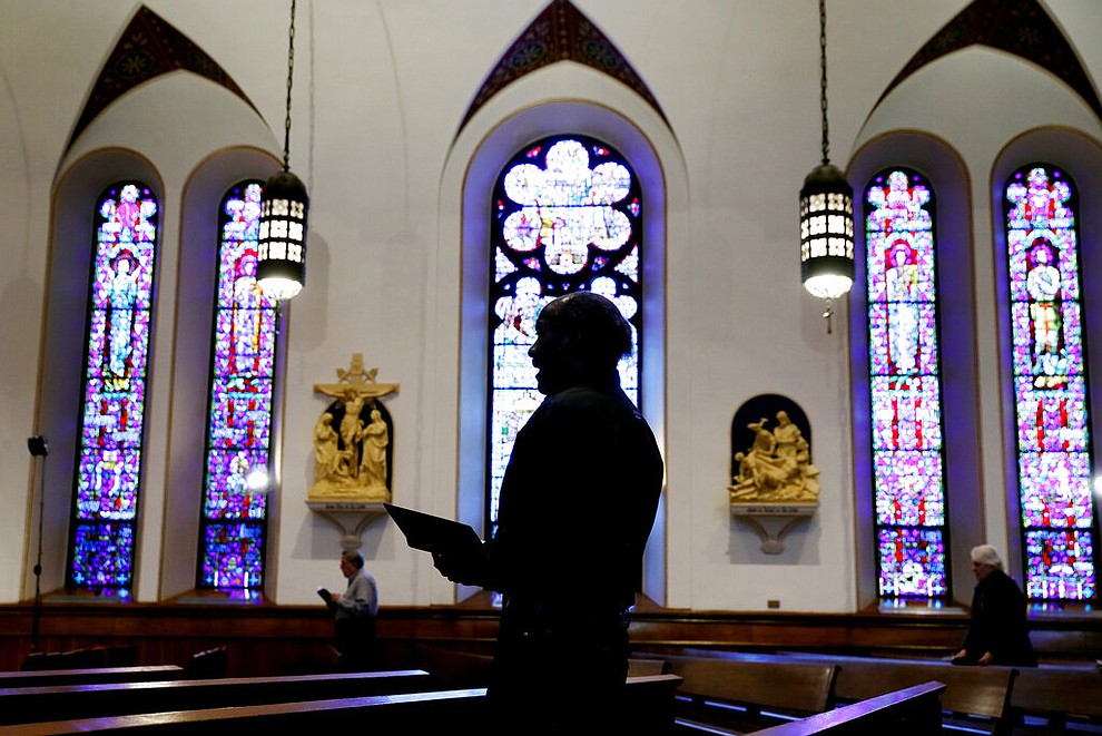 A church member prays during a Good Friday service at St. Ambrose Cathedral, Friday, April 10, 2020, in Des Moines, Iowa. COVID-19 causes mild or moderate symptoms for most people, but for some, especially older adults and people with existing health problems, it can cause more severe illness or death. (AP Photo/Charlie Neibergall)