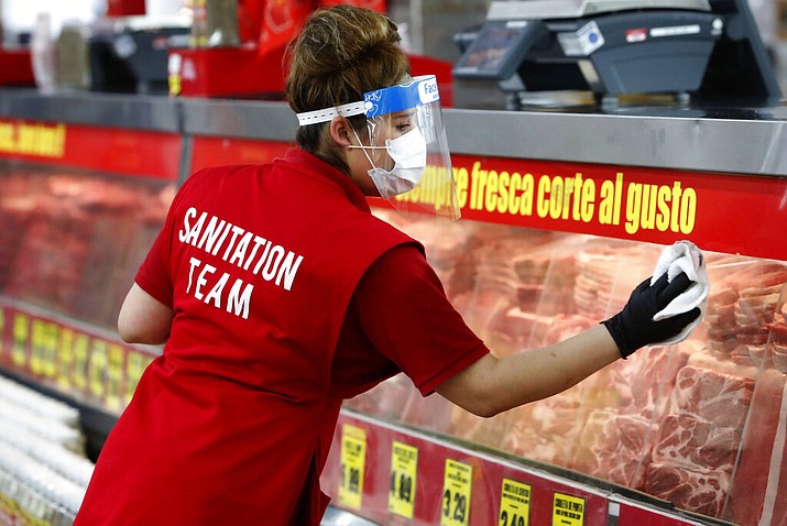 Amid concerns of the spread of COVID-19, Belia Alvarado wipes the meat counter display at El Rancho grocery store in Dallas, Monday, April 13, 2020. (AP Photo/LM Otero)
