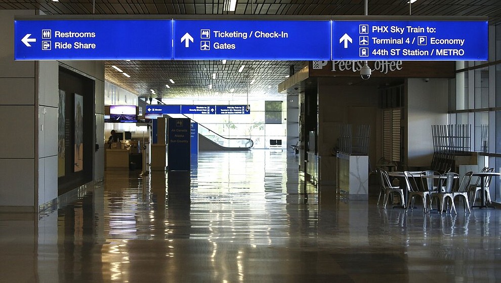An empty hallway leads to the baggage claim area at Phoenix Sky Harbor International Airport on Tuesday, April 14, 2020, in Phoenix. The coronavirus outbreak has caused a significant decrease in air travel. (AP Photo/Ross D. Franklin)
