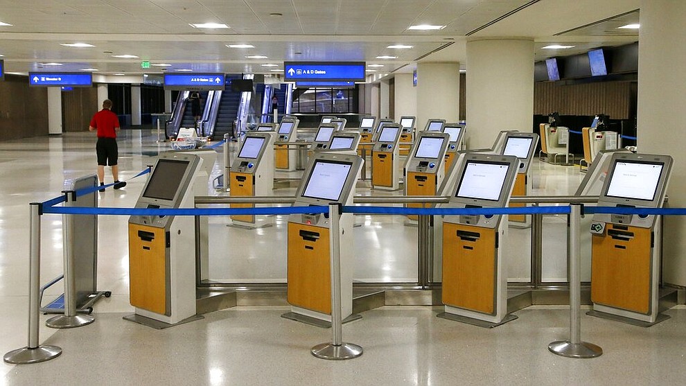American Airlines check-in kiosks are cordoned off at Phoenix Sky Harbor International Airport on Tuesday, April 14, 2020, in Phoenix. The coronavirus outbreak has caused a significant decrease in air travel. (AP Photo/Ross D. Franklin)