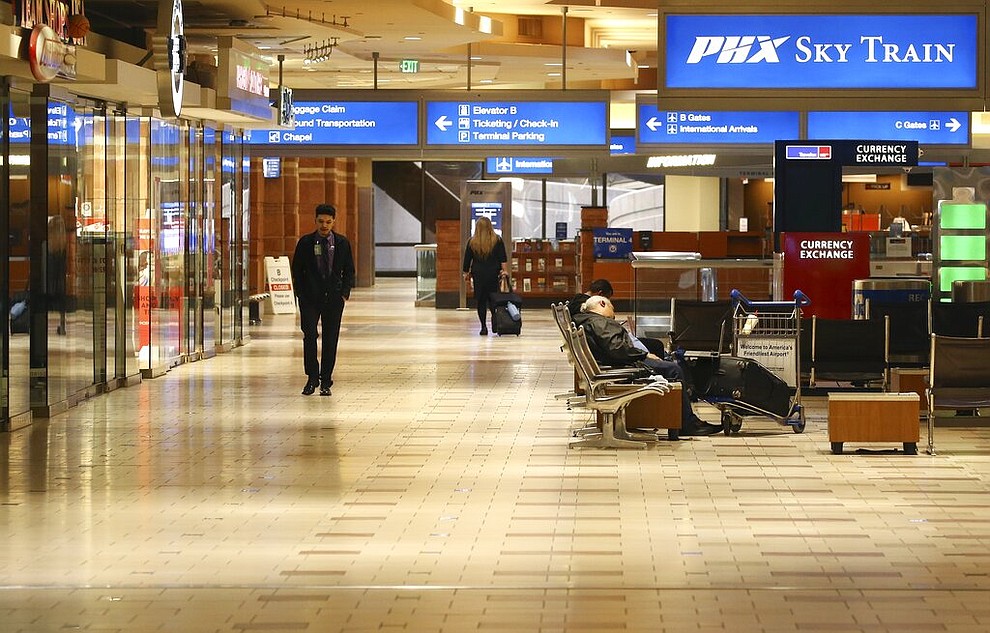 A nearly empty terminal shows few passengers at Phoenix Sky Harbor International Airport Tuesday, April 14, 2020, in Phoenix. The coronavirus has caused a significant decrease in air travel. (AP Photo/Ross D. Franklin)