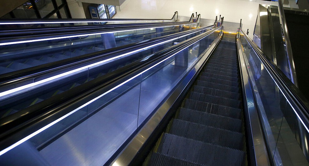 Empty escalators go down to the baggage claim area at Phoenix Sky Harbor International Airport Tuesday, April 14, 2020, in Phoenix. The coronavirus has caused a significant decrease in air travel. (AP Photo/Ross D. Franklin)